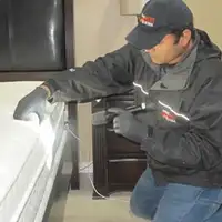 Bed bug inspection technician checking a mattress and bed frame for signs of infestation in San Francisco, CA