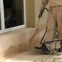 General pest control technician spraying exterior perimeter around a home in San Francisco, CA