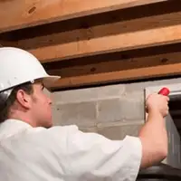 Termite inspection technician checking a basement wall and framing for termite activity in San Francisco, CA